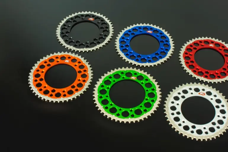 Renthal Twinring Kettenräder in Orange, Schwarz, Blau, Rot, Grün und Silber auf schwarzem Hintergrund