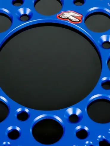 Blaues, leichtes Renthal-Kettenrad aus Aluminium mit Gewichtserleichterungsbohrungen und Mud-Groove-Design.