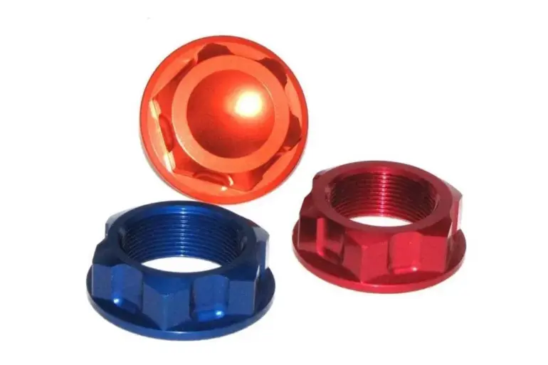 Drei Steuerkopfmutter aus Metall in Blau, Rot und Orange auf weißem Hintergrund.