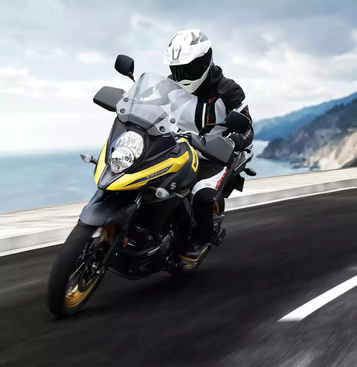 Motorradfahrer auf einer gelb-schwarzen Suzuki V-Strom 650XT Touring Edition auf Küstenstraße