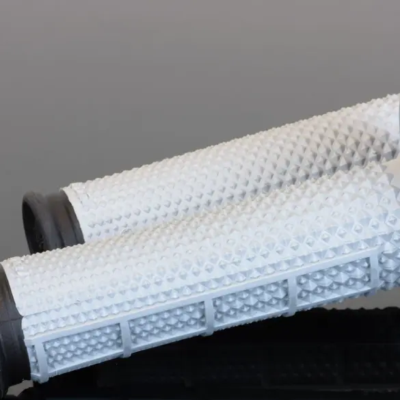 Weiße Tapered MX Griffe mit markanter Diamantstruktur und breitem Flansch auf spiegelndem Untergrund
