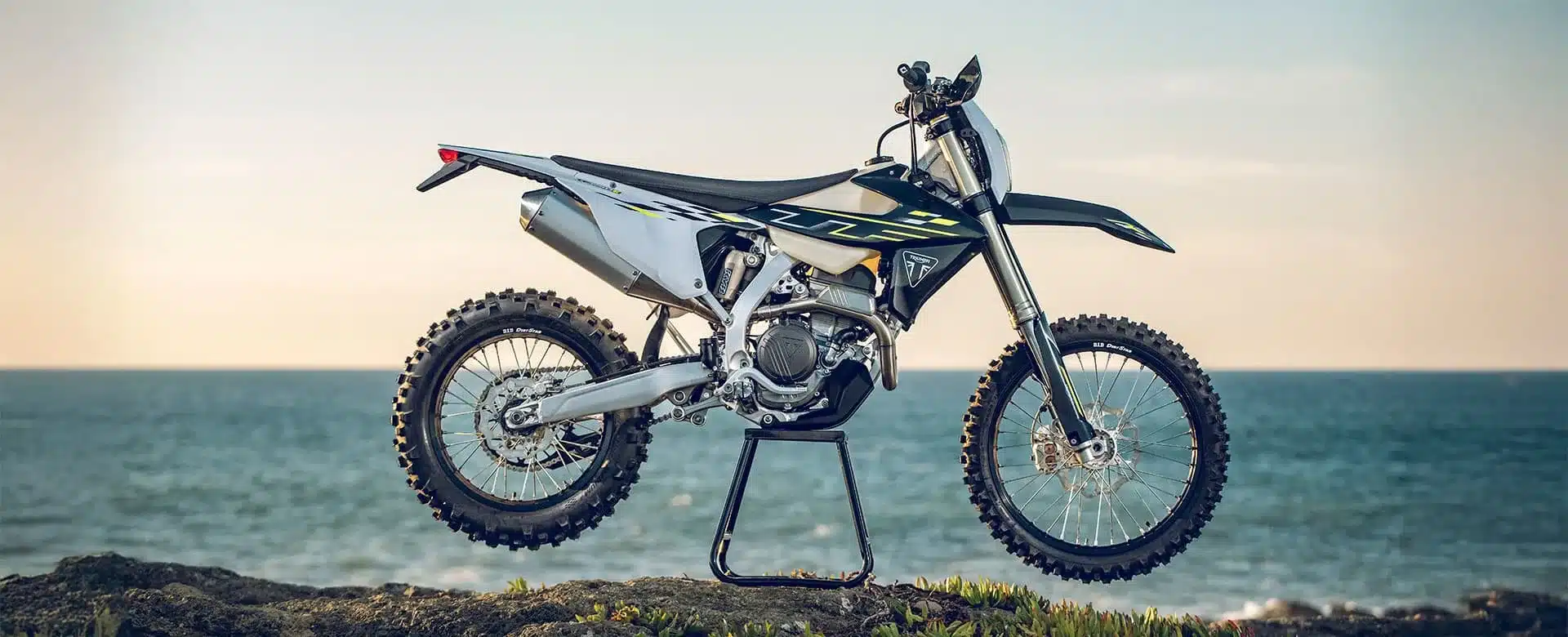 Triumph TF 250-E Enduro-Motorrad mit Aluminiumrahmen und Offroad-Ausstattung vor Meereskulisse