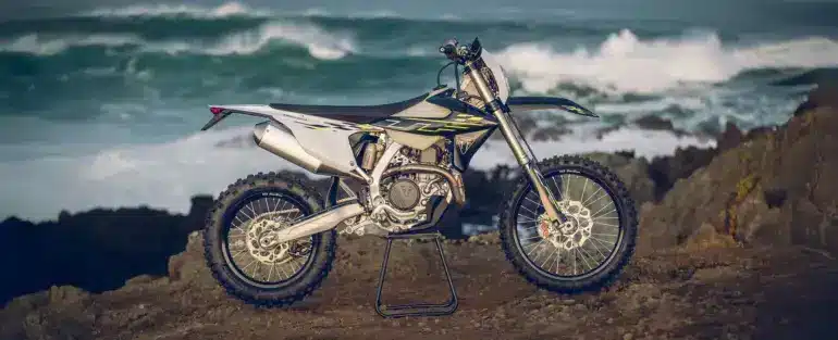 Triumph TF 450-E Enduro-Motorrad seitlich auf Felsen vor dem Ozean