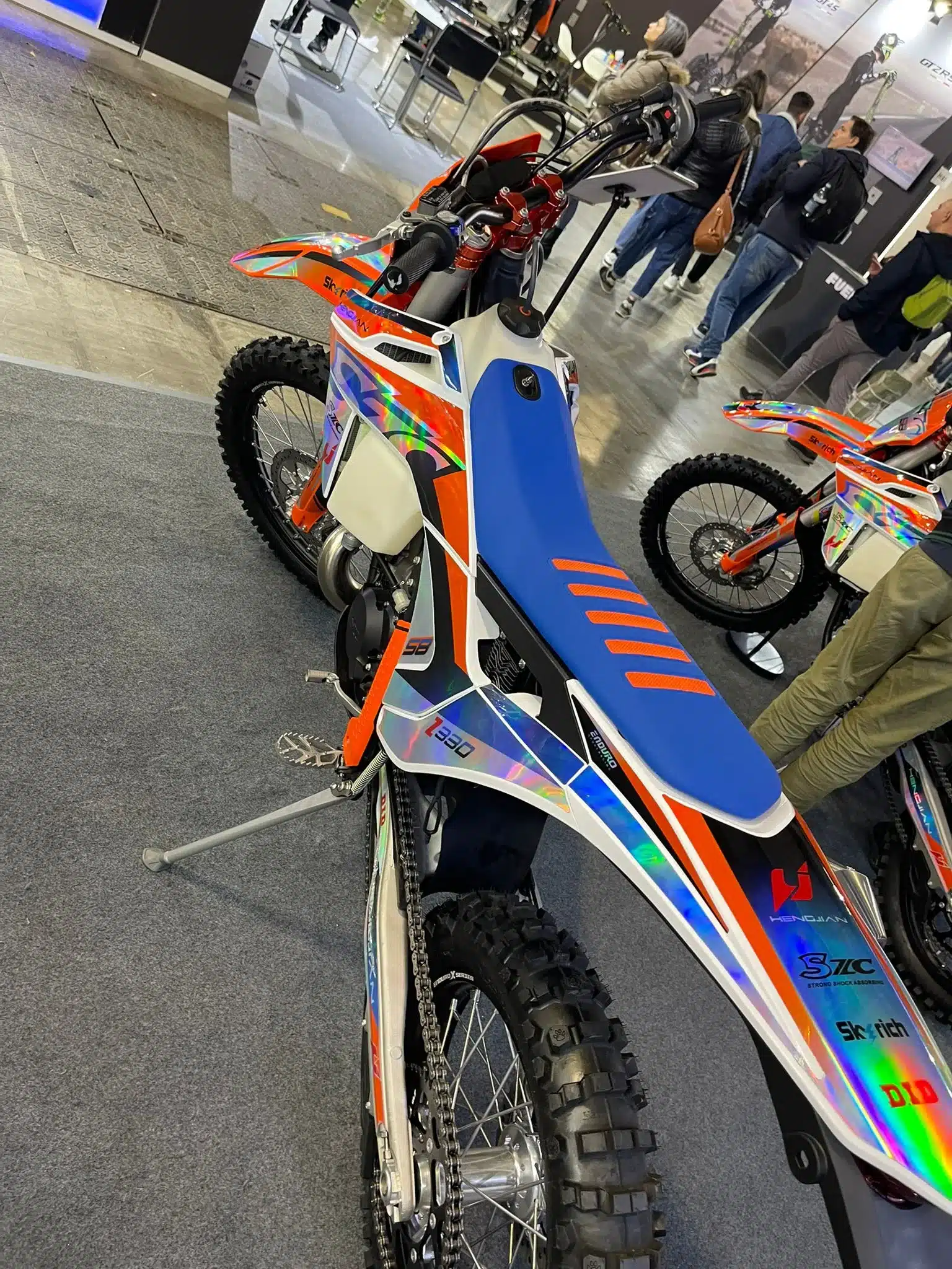 Heckansicht der Hengjian S8 Z300 Race, ein sportliches Enduro-Motorrad mit blauer Sitzbank und auffälligen Renndekoren, ausgestellt auf einer Messe.