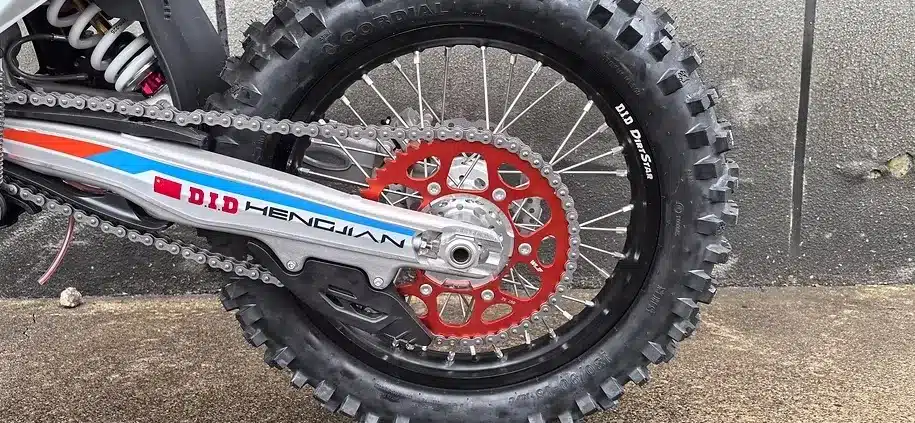 Nahaufnahme des Hinterrads einer Hengjian S8 Z300 Race mit grobem Offroad-Reifen und Kettensystem.