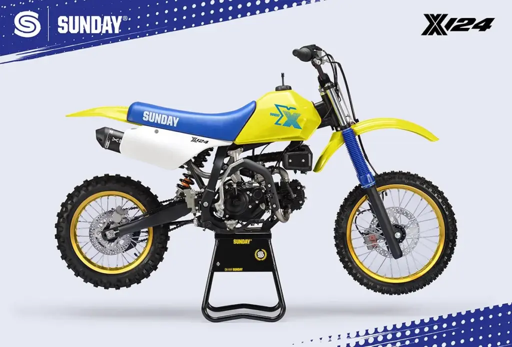 Seitenansicht der Sunday X 124 Yellow 2025, einem gelben Vintage-Cross-Motorrad mit blauem Sitz und Retro-Optik.