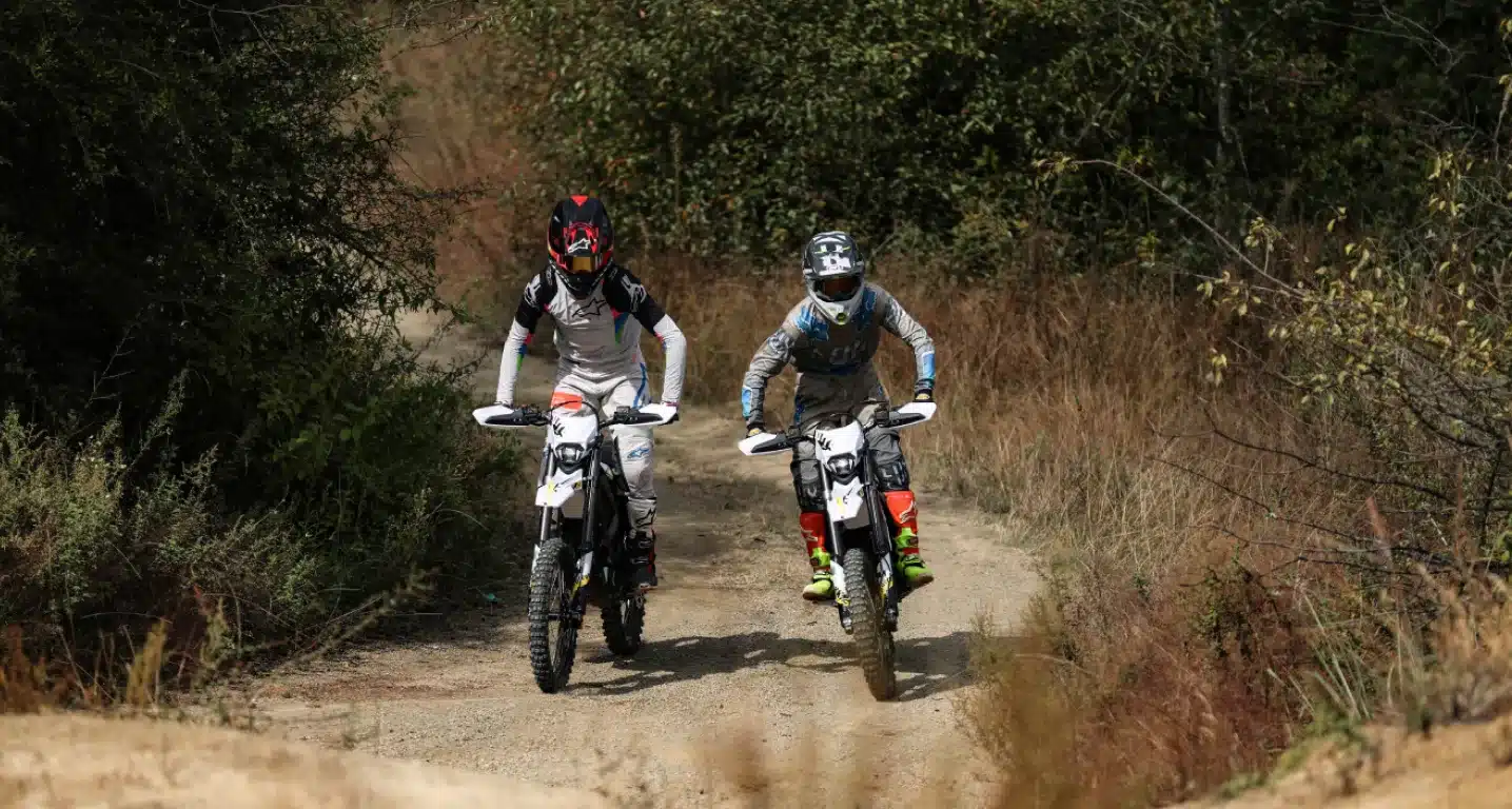 Zwei Personen fahren mit der Sur-Ron Ultra Bee C 2025 elektrisch angetrieben durch unbefestigtes Gelände