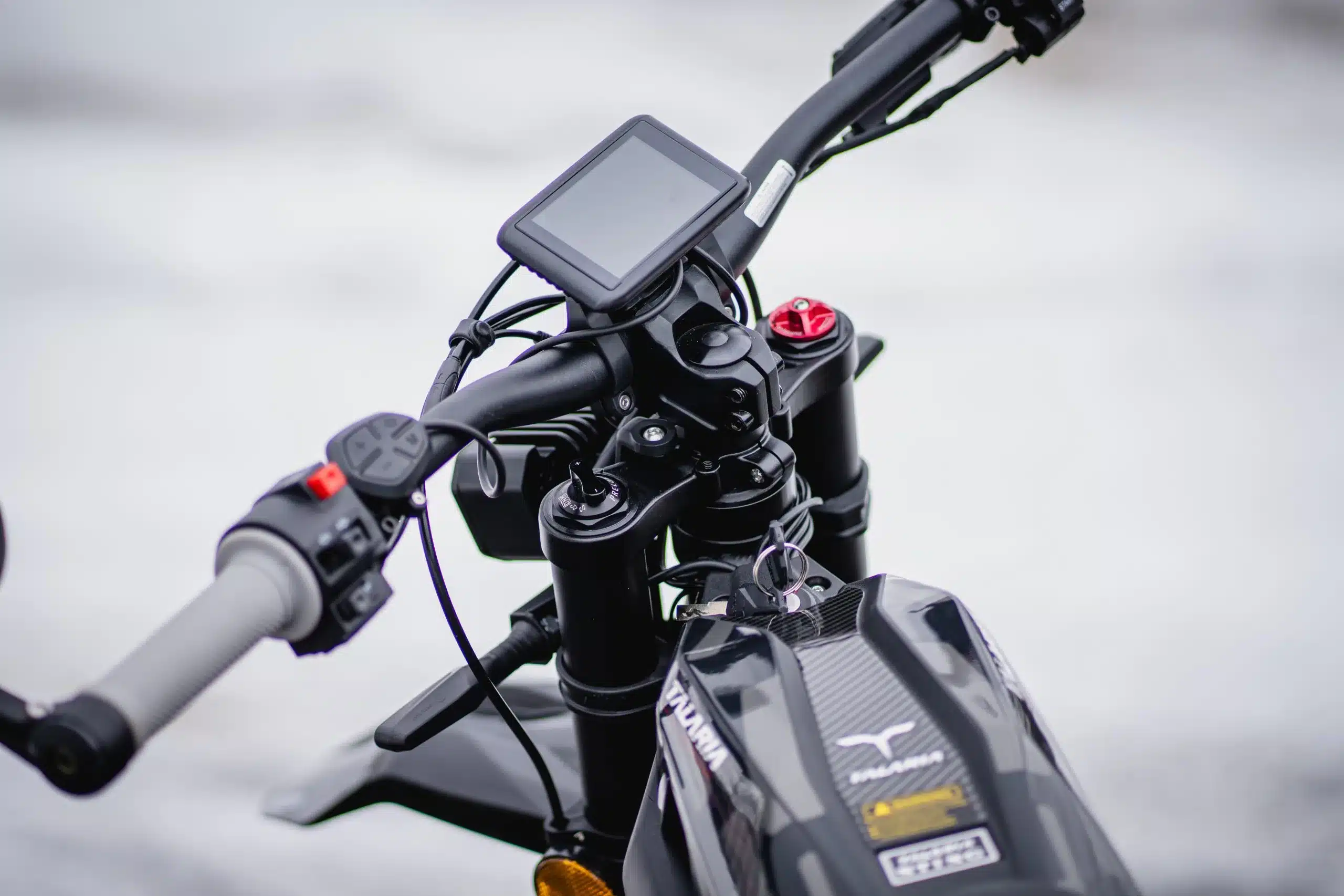 Detailansicht des Cockpits und Lenkers der Talaria Sting R L1e mit OLED-Display, Bedienelementen und Zündschlüssel.