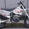 Seitliche Gesamtaufnahme der GPX FSE250S Enduro mit grobstolligen Reifen, Stahlrohrrahmen und moderner Verkleidung, abgestellt vor einer Betonwand.