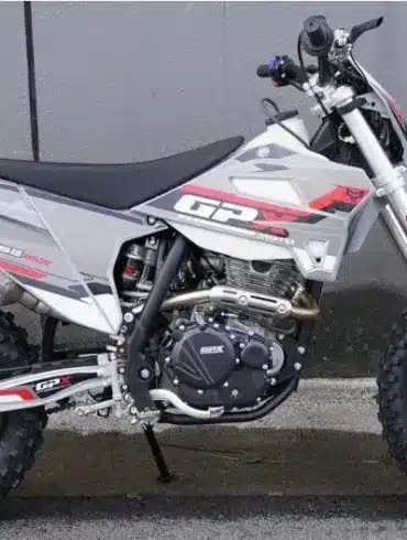 Seitliche Gesamtaufnahme der GPX FSE250S Enduro mit grobstolligen Reifen, Stahlrohrrahmen und moderner Verkleidung, abgestellt vor einer Betonwand.