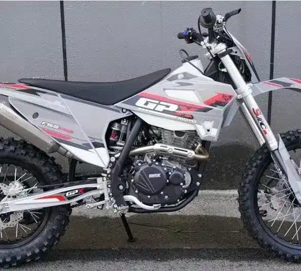 Seitliche Gesamtaufnahme der GPX FSE250S Enduro mit grobstolligen Reifen, Stahlrohrrahmen und moderner Verkleidung, abgestellt vor einer Betonwand.