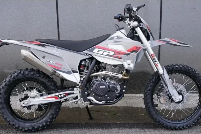 Seitliche Gesamtaufnahme der GPX FSE250S Enduro mit grobstolligen Reifen, Stahlrohrrahmen und moderner Verkleidung, abgestellt vor einer Betonwand.
