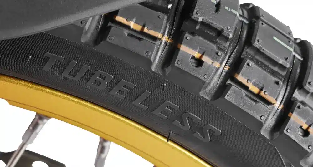 Nahaufnahme eines Tubeless-Enduroreifens mit großem Profil auf einer goldenen Speichenfelge, geeignet für die Rieju Aventura 500.