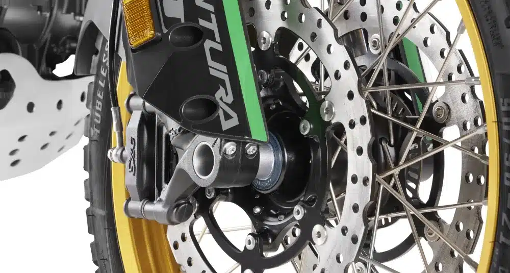 Nahaufnahme des Vorderrads einer Rieju Aventura 500 mit goldener Speichenfelge, Bremsscheiben und Upside-down-Gabel