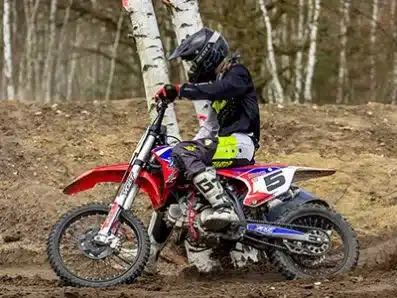 Jugendlicher fährt eine RXF Freeride 150cc im Gelände durch eine sandige Kurve.