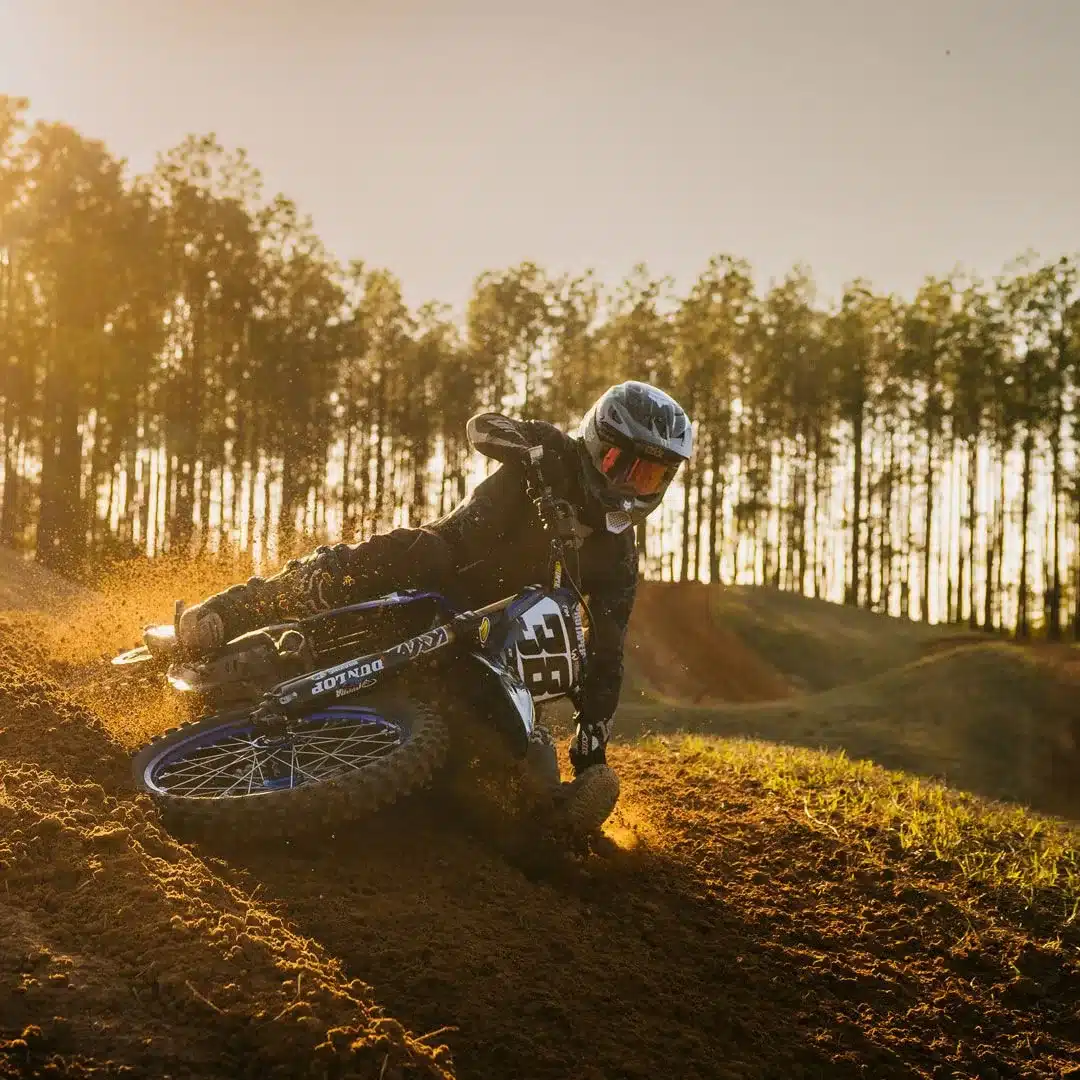 Motocross-Fahrer trägt die Signature-Kollektion mit Flexair Ausrüstung, Helm und Brille während einer Kurve im Gelände bei Sonnenuntergang.