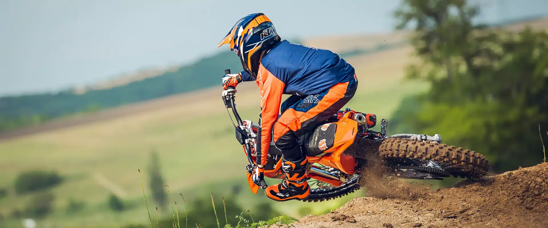 Motocross-Fahrer mit KTM 85 SX 19/16 Motorrad in Kurvenlage auf sandiger Rennstrecke.