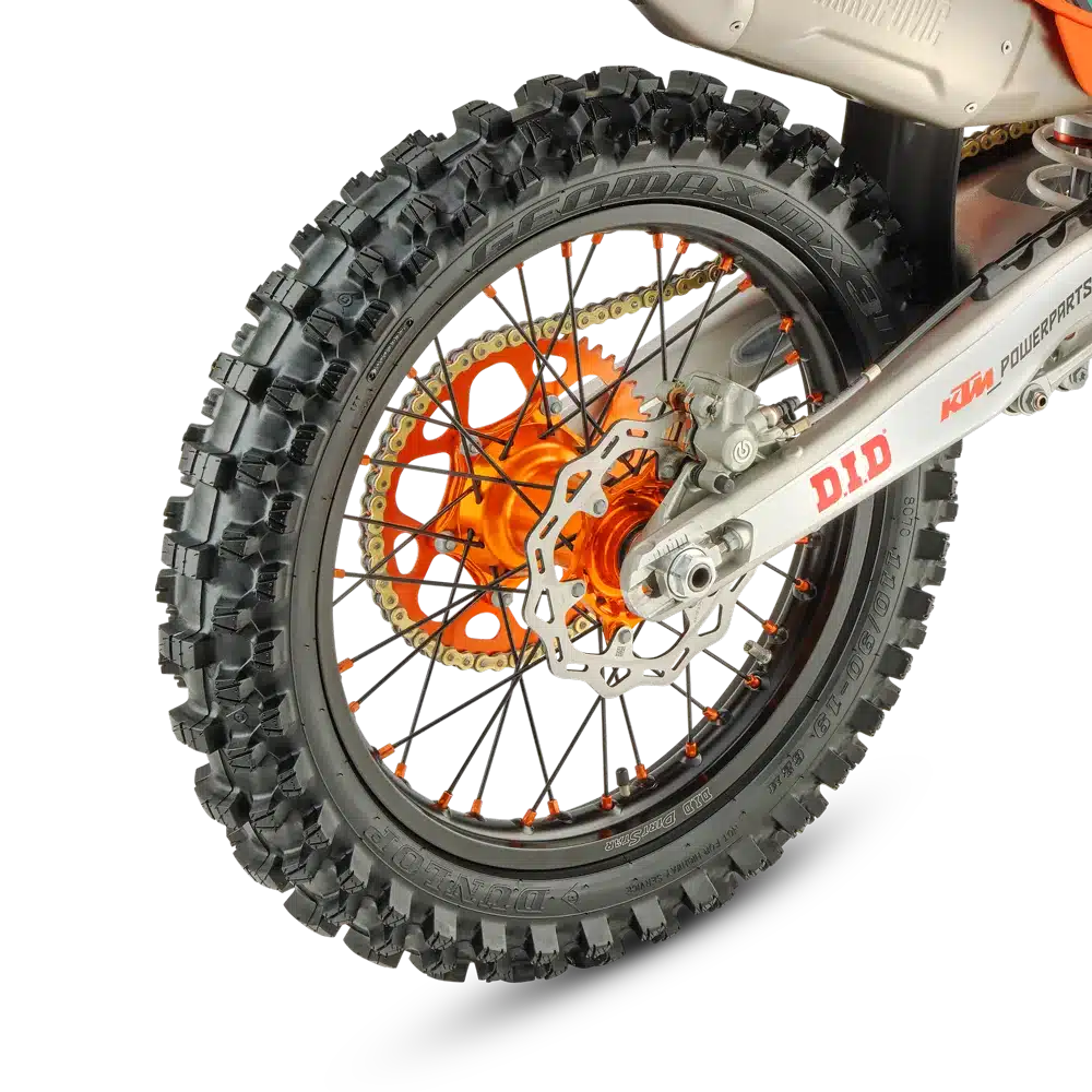 Das Hinterrad einer KTM 250 SX-F Factory Edition 2026 mit grobstolligem Dunlop Geomax MX34-Reifen, D.I.D DirtStar-Felge, schwarz-orangenen Speichen und goldener Kette