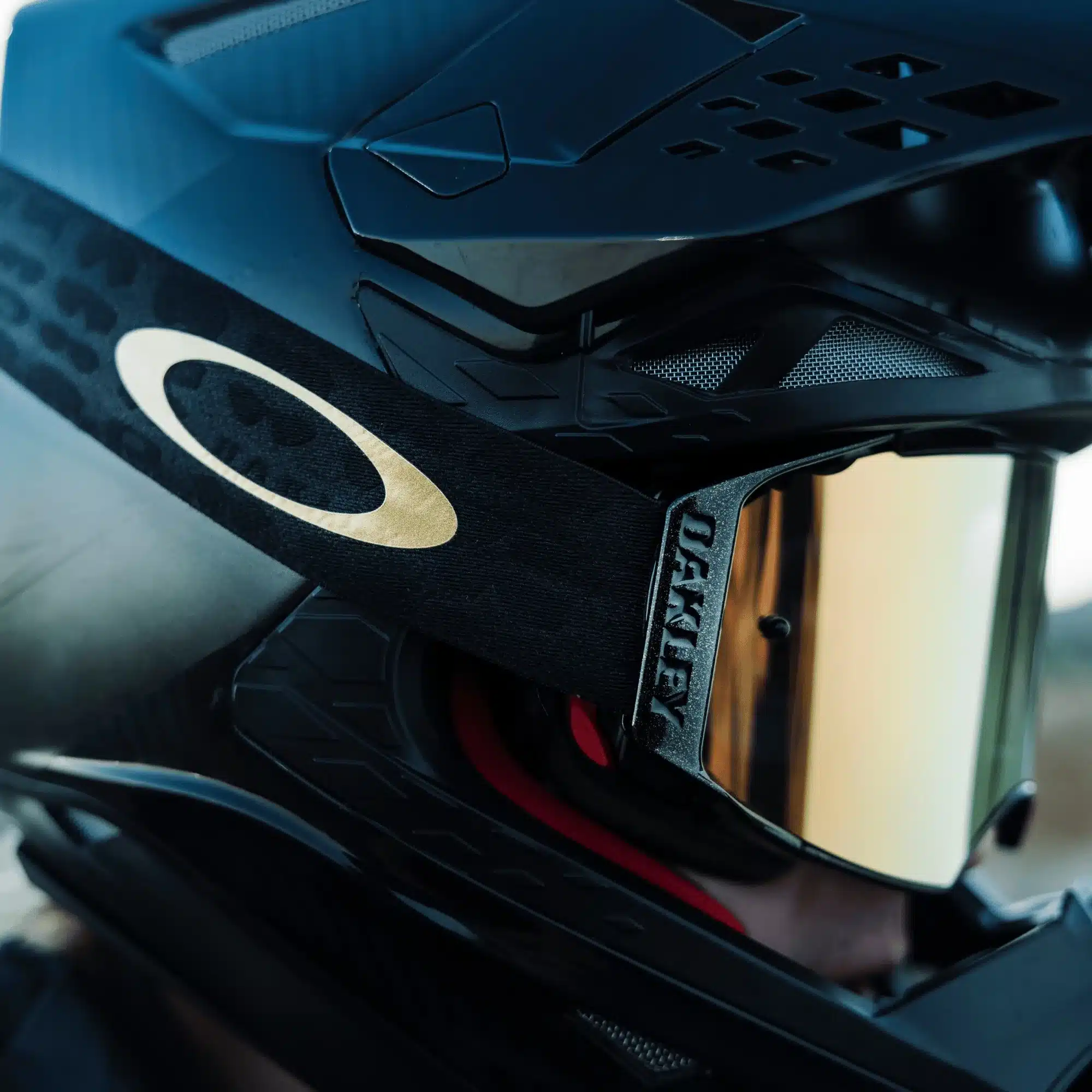 Oakley Airbrake MX Motocross-Brille mit 24K-Iridium-Glas an einem schwarzen Helm in Nahaufnahme.