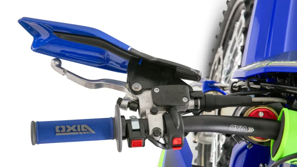 Nahaufnahme des Lenkers der 125 SE FACTORY 2027 mit blauem Handprotektor und Bedienelementen.