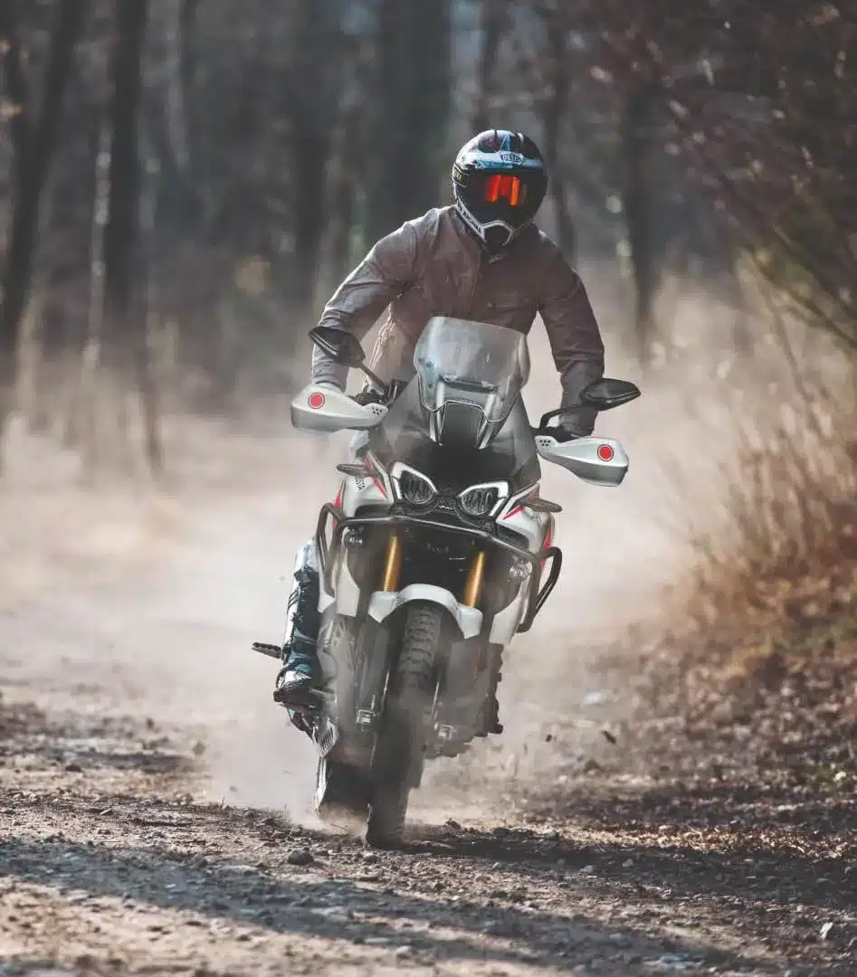 Fahrer mit Helm auf einer MV Agusta Enduro Veloce 2026 auf einer Schotterpiste im Wald.