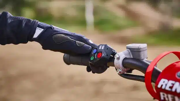 Motorradlenker der Honda CRF450R mit Bedientasten für elektronische Fahrhilfen auf einer Motocross-Strecke.