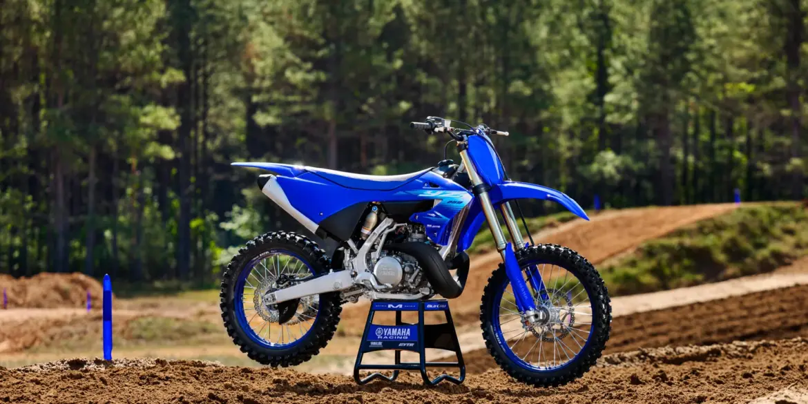 Yamaha YZ250 Motocross-Motorrad steht auf einer lehmigen Rennstrecke vor Waldkulisse.