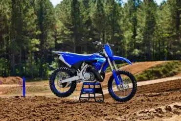 Yamaha YZ250 Motocross-Motorrad steht auf einer lehmigen Rennstrecke vor Waldkulisse.