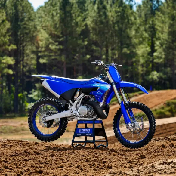 Yamaha YZ250 Motocross-Motorrad steht auf einer lehmigen Rennstrecke vor Waldkulisse.