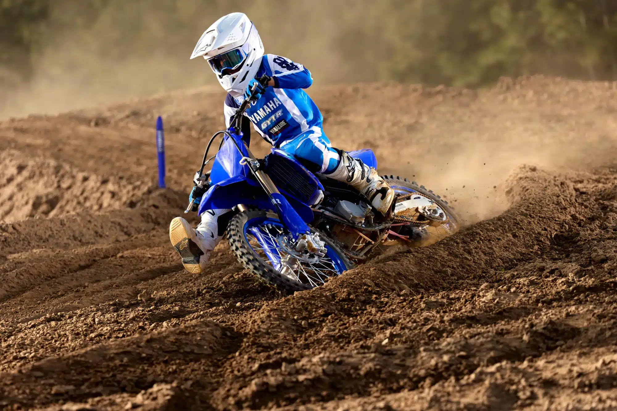 Ein Jugendlicher fährt eine Yamaha YZ85 im blauen Design über eine Motocross-Strecke