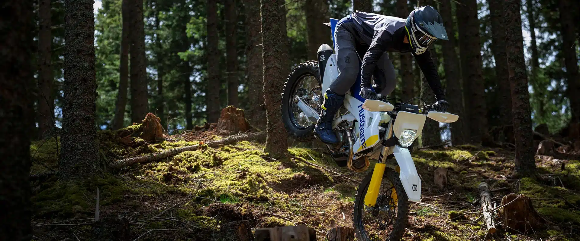 Enduro-Fahrer mit Husqvarna FE 250 durchfährt einen bewaldeten, anspruchsvollen Trail
