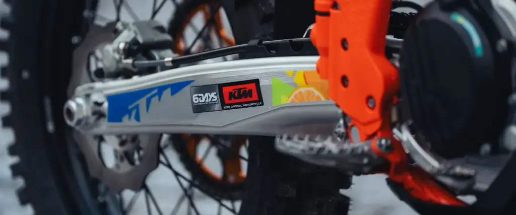 Detail der Schwinge einer KTM 350 EXC-F 6DAYS mit 6DAYS- und KTM-Branding sowie orangem Rahmenschutz