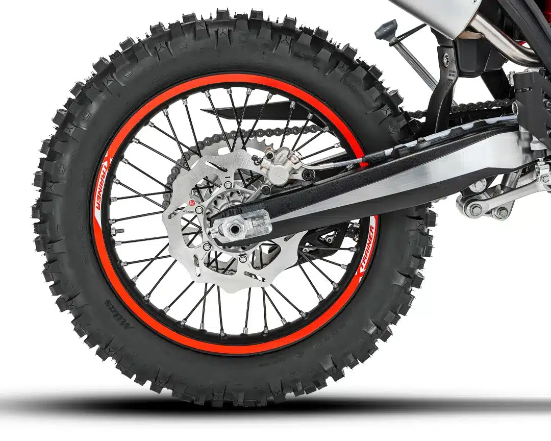 Das Hinterrad der Beta Xtrainer 200 2T mit Stollenreifen, oranger Felgenaufkleber und neuer Wave-Bremsscheibe.