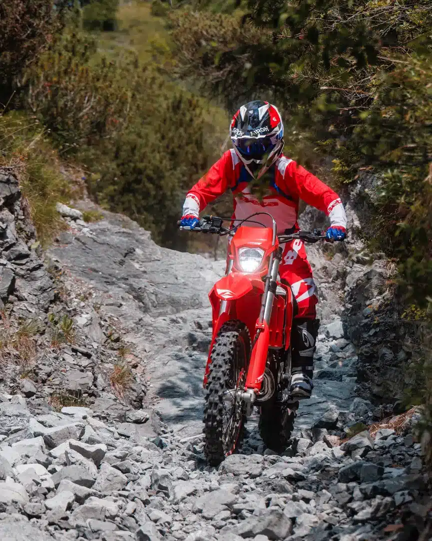Beta Xtrainer 200 2T Enduro-Motorrad wird von einem Fahrer auf einem steinigen Offroad-Pfad gefahren.