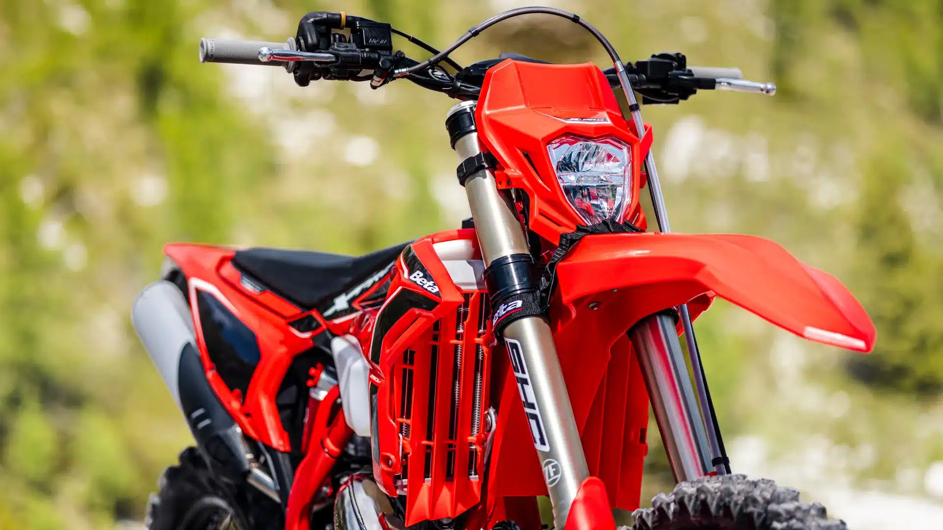 Detailansicht der Beta RR X-PRO 2T 200 Enduro von vorne, leuchtend rotes Design und Federungskomponenten sichtbar.
