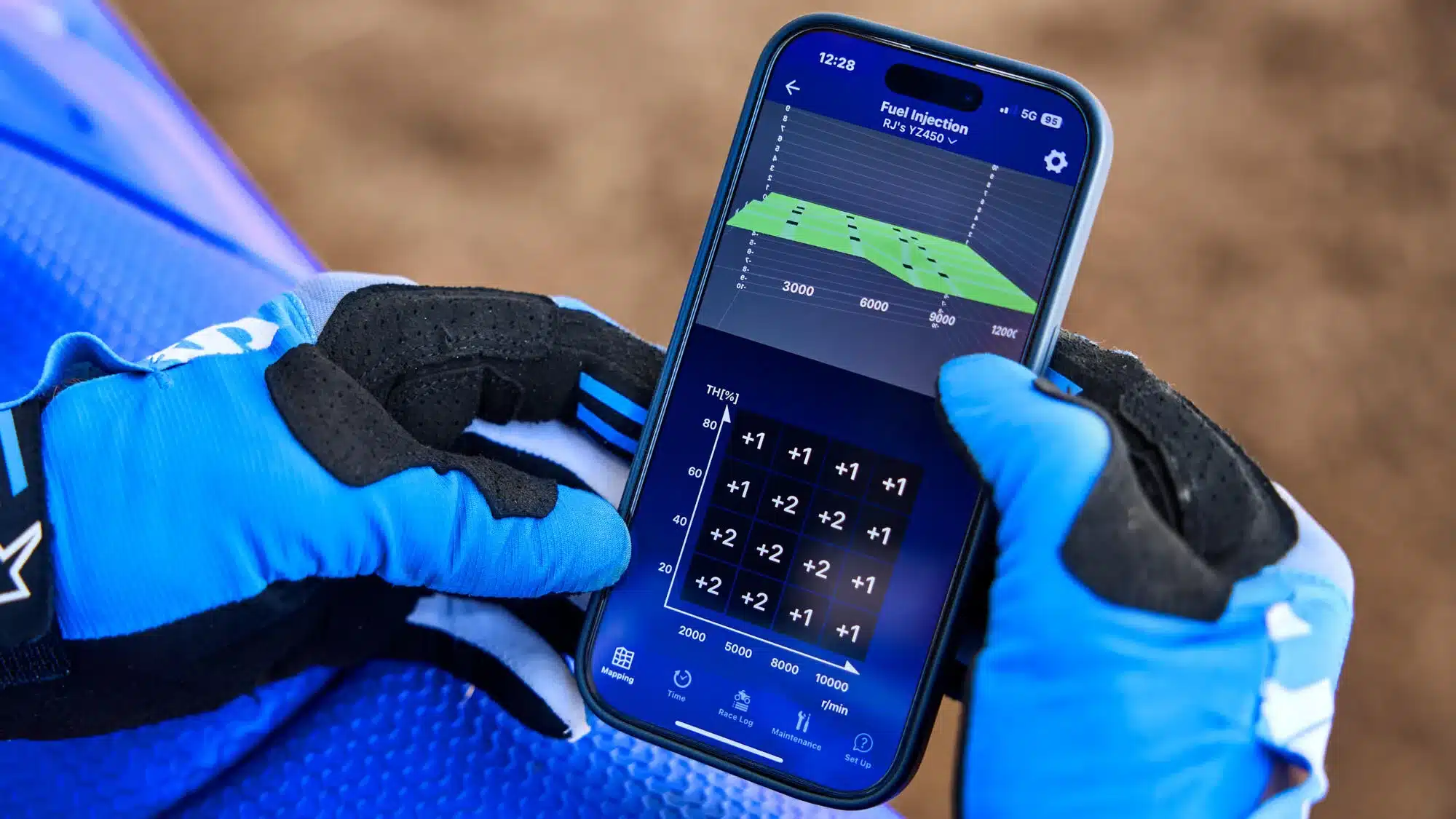 Motocross-Hand mit Handschuh bedient die Yamaha Power Tuner-App auf einem Smartphone