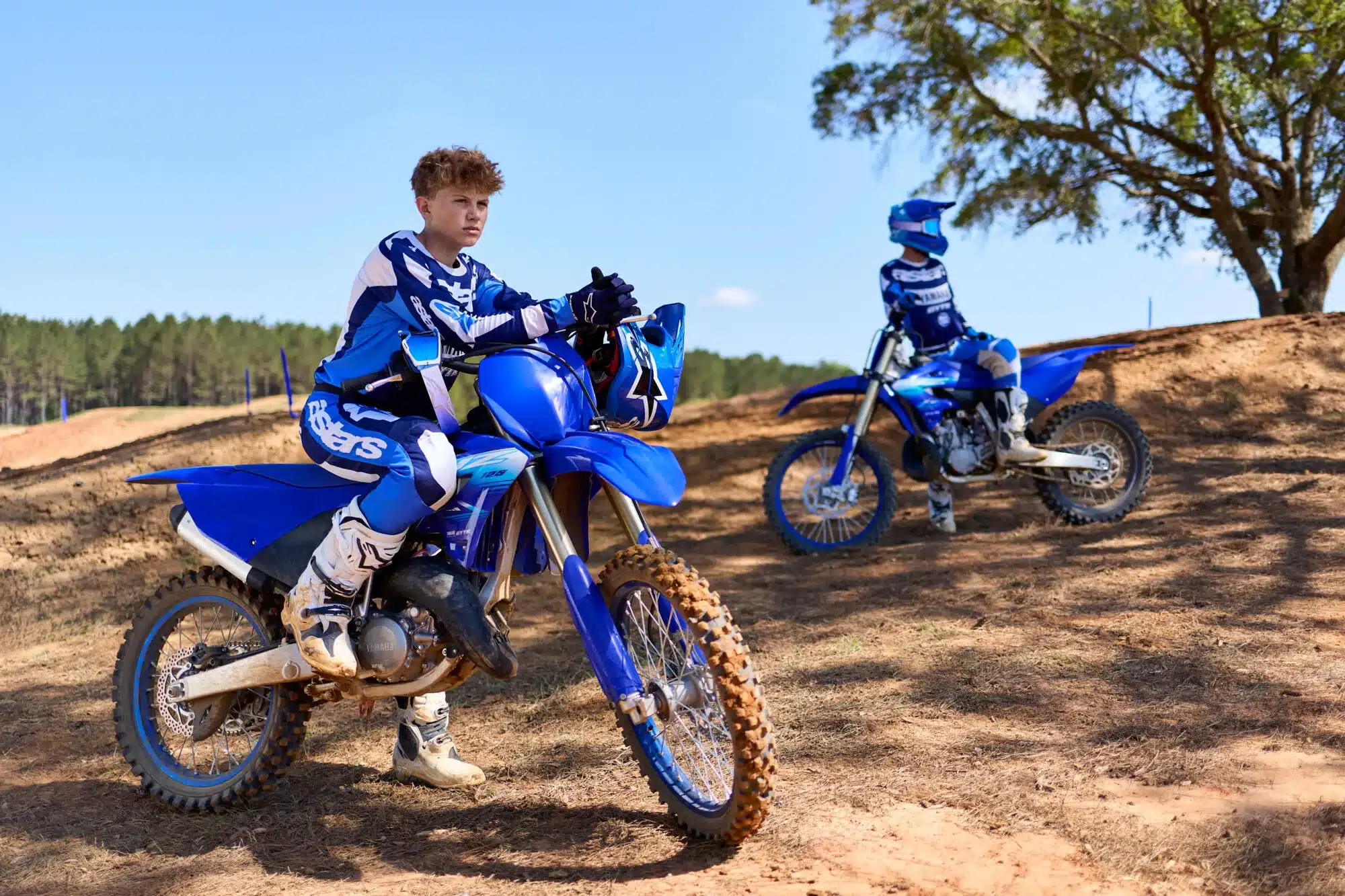 Zwei Jugendliche auf Yamaha YZ125 Motocross-Motorrädern in blauer Rennkleidung auf einer Offroad-Strecke