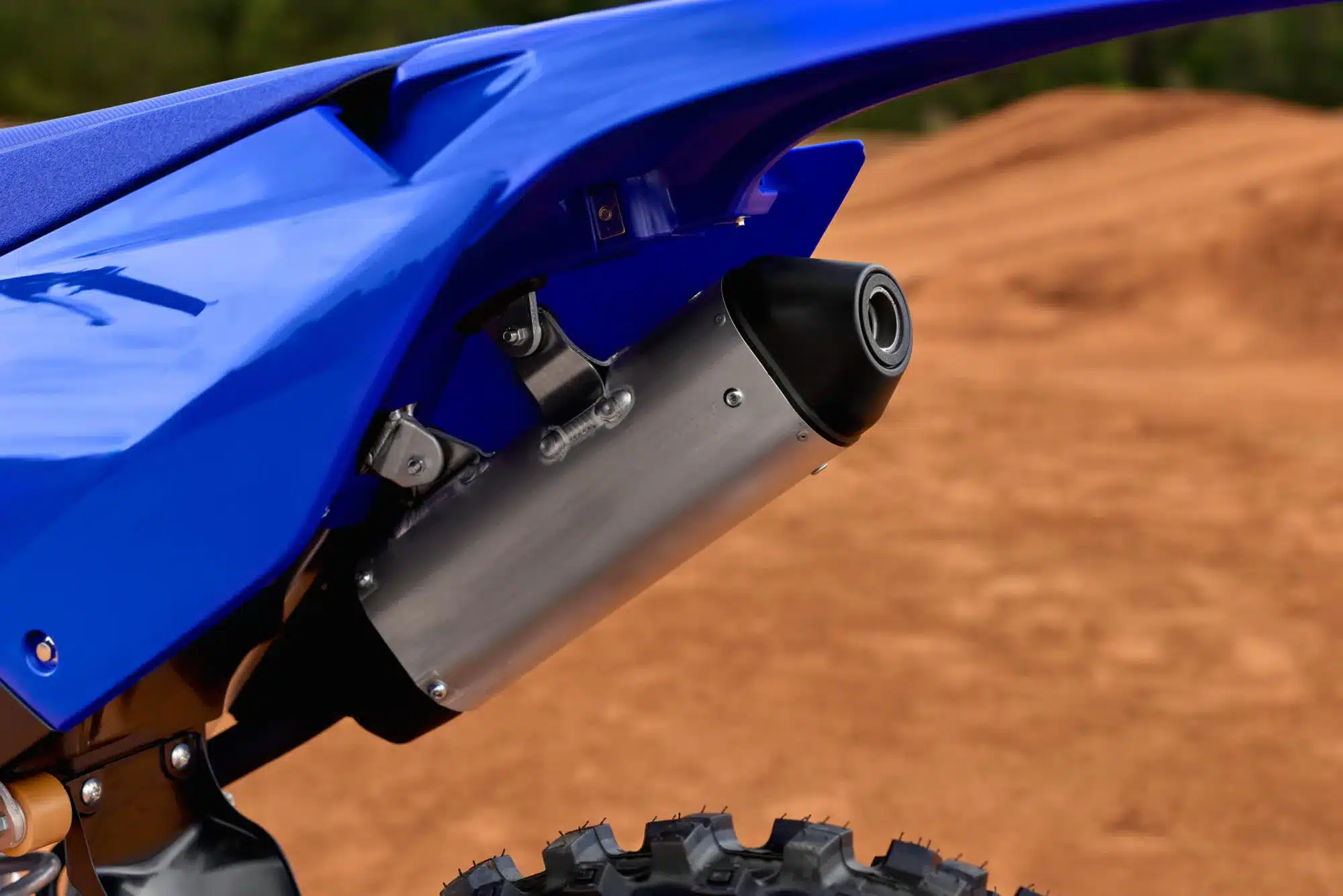 Nahaufnahme des Auspuffs einer Yamaha YZ125 vor einer Motocross-Strecke