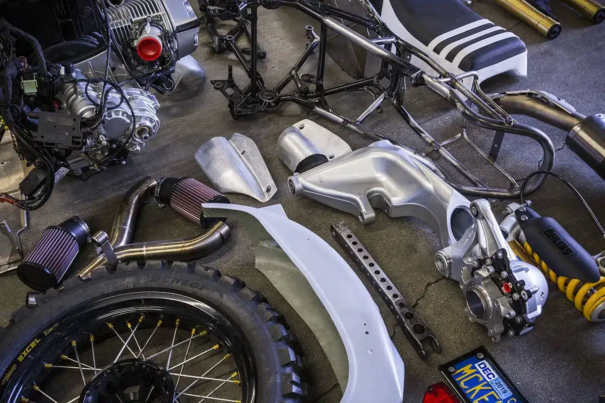 Motorradteile der RSD Dakar GS, darunter Motor, Rahmen, Luftfilter, Federbein, Felge und Sitzbank, ausgebreitet in einer Werkstatt