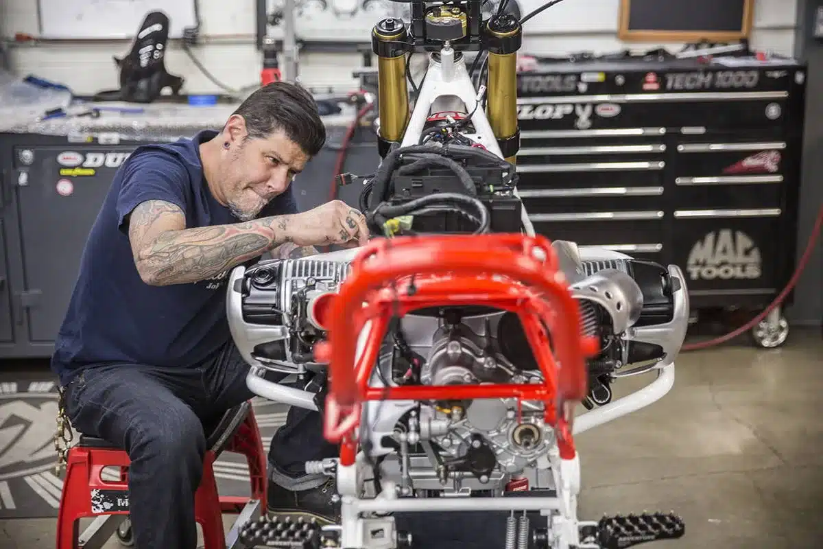Mechaniker baut Motorrad RSD Dakar GS in Werkstatt um, Fokus auf Motor und Rahmen