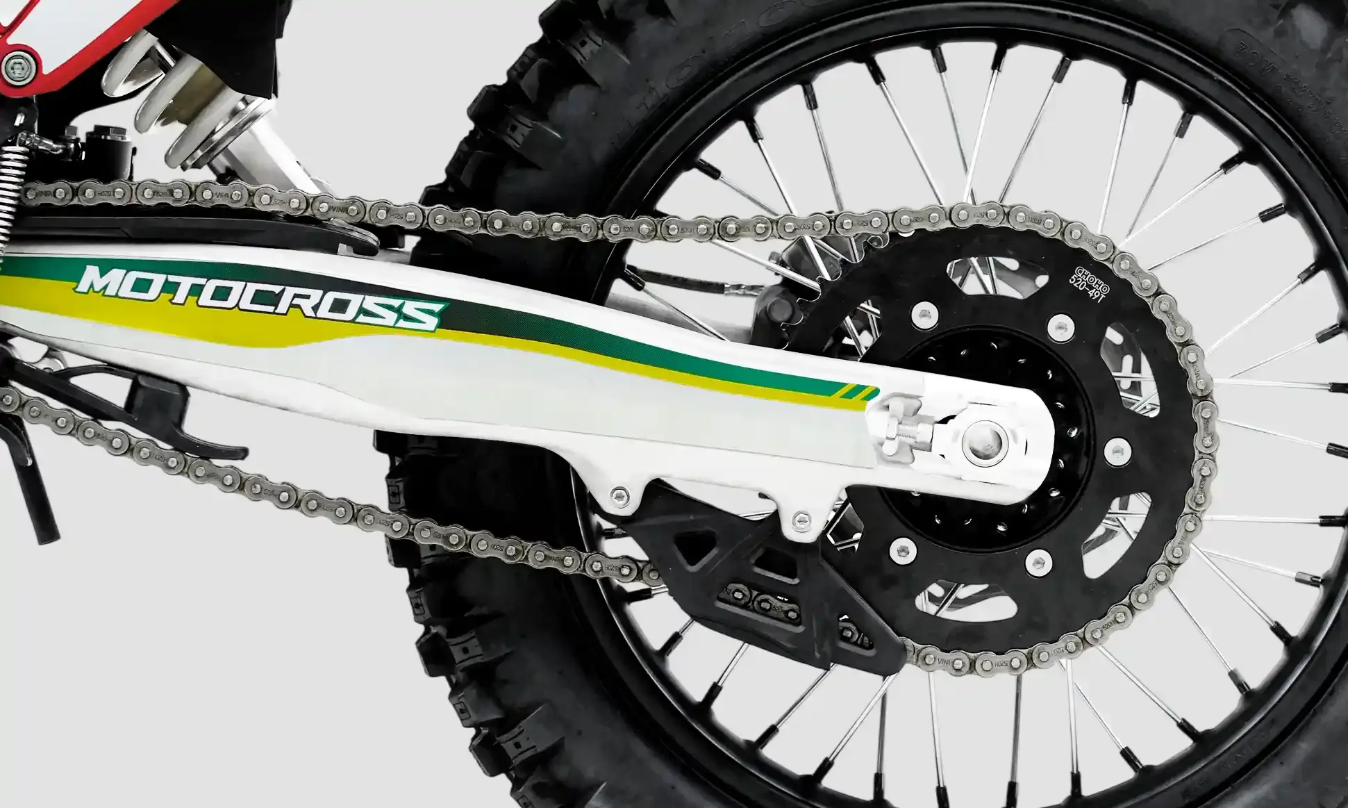Nahaufnahme des Kettenantriebs und der Schwinge eines Motocross- oder Enduro-Motorrads mit grobstolligem Hinterradreifen