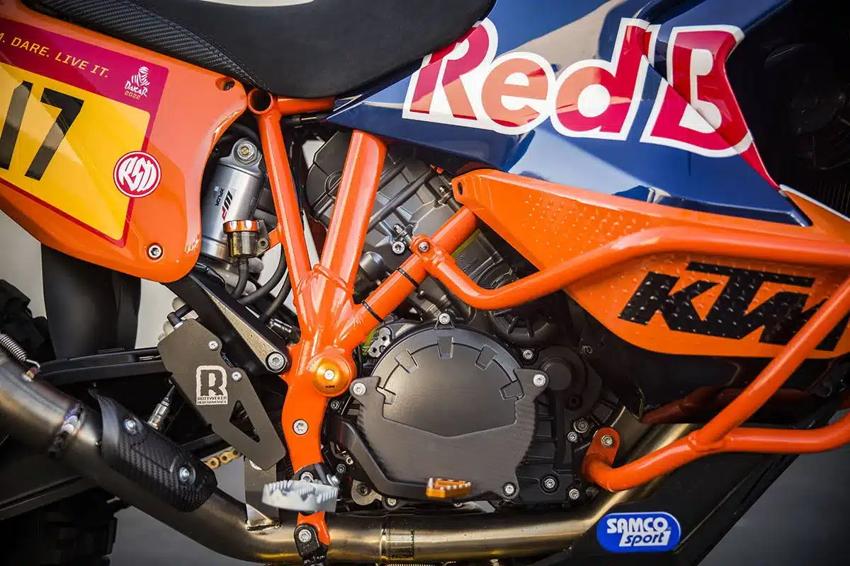 Nahaufnahme des Mittelteils einer umgebauten KTM 1290 Paris Dakar mit auffälligem orangefarbenem Rahmen und Dakar-Beklebung