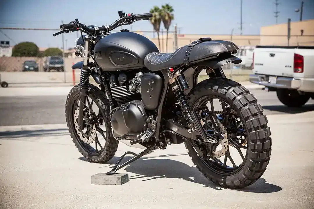 Custom Scrambler Motorrad Schlege Triumph mit mattschwarzer Lackierung, groben Stollenreifen und sportlichem Heck.