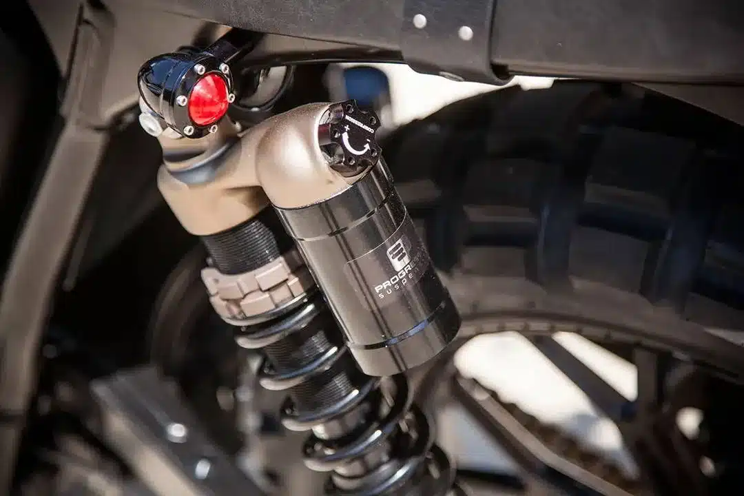 Nahaufnahme eines Progressive-970-Series-Federbeins an einem umgebauten Triumph Scrambler Motorrad mit grobstolligem Reifen.
