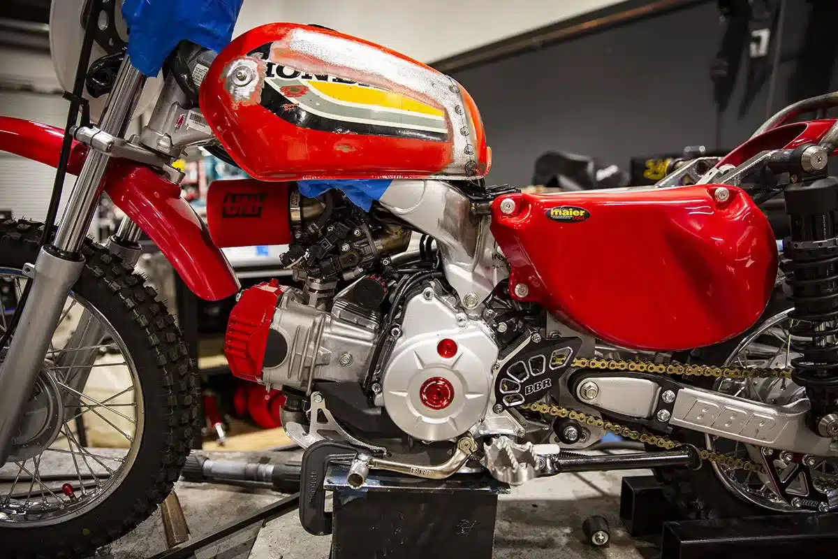Nahaufnahme des Umbaus einer Honda CRF110F zur Wee Man CRF 110 mit Twin-Shock-Fahrwerk und roten Verkleidungen.