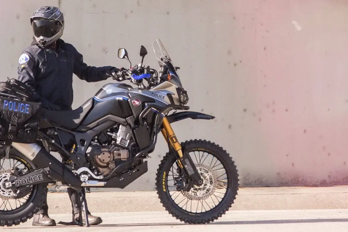 Honda Africa Twin Polizeimotorrad Redondo PD mit kompletter Einsatz-Ausrüstung, seitlich im Profil, Polizist in voller Montur.
