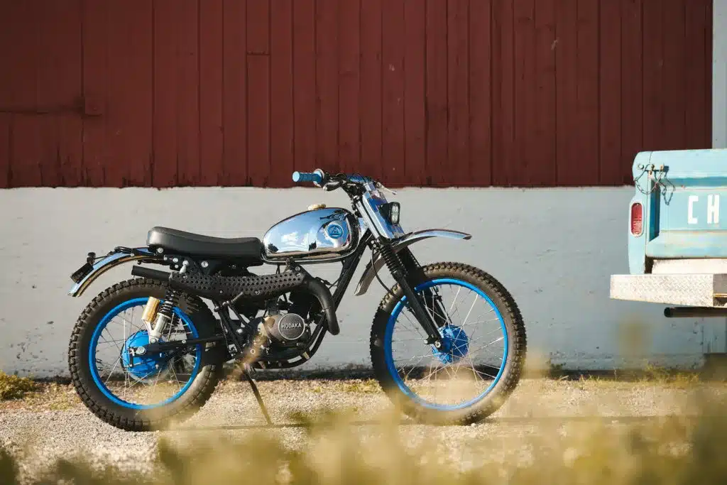 Seitliche Ansicht einer umgebauten Hodaka Wombat von 1973 mit blau akzentuierten Felgen und verchromtem Tank im Vintage-Stil