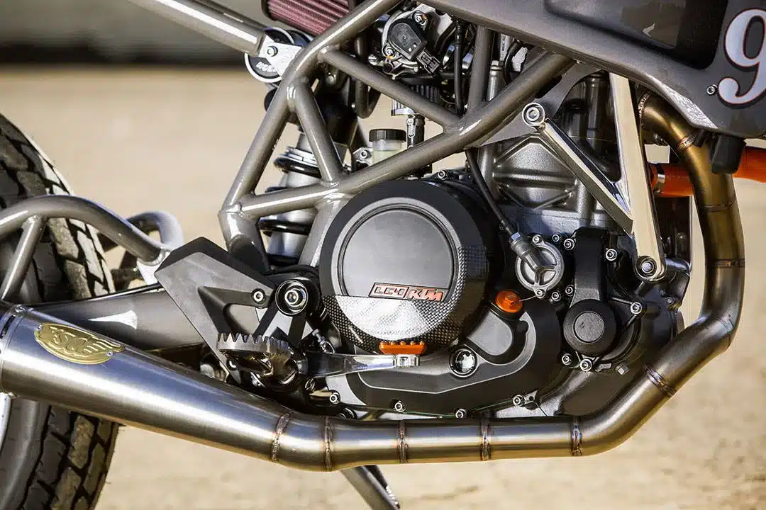 Detailansicht vom Motor und Rahmen der RSD KTM 690 Tracker mit sichtbarem Auspuff und Fahrwerkskomponenten.