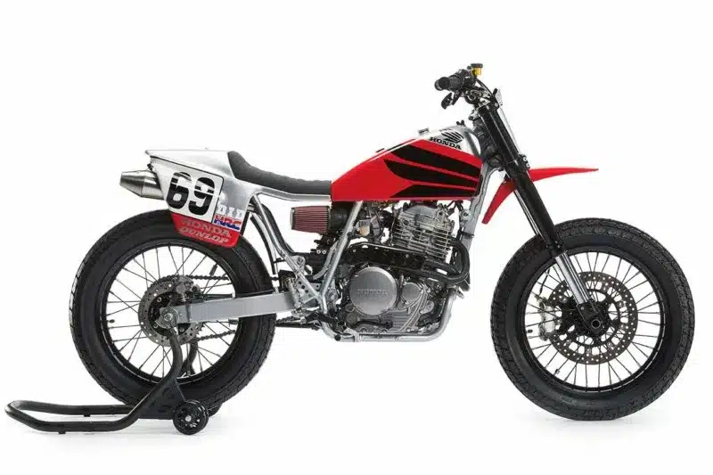 Seitenansicht einer umgebauten Honda XR650L im Flat-Track-Stil mit roten und schwarzen Akzenten.