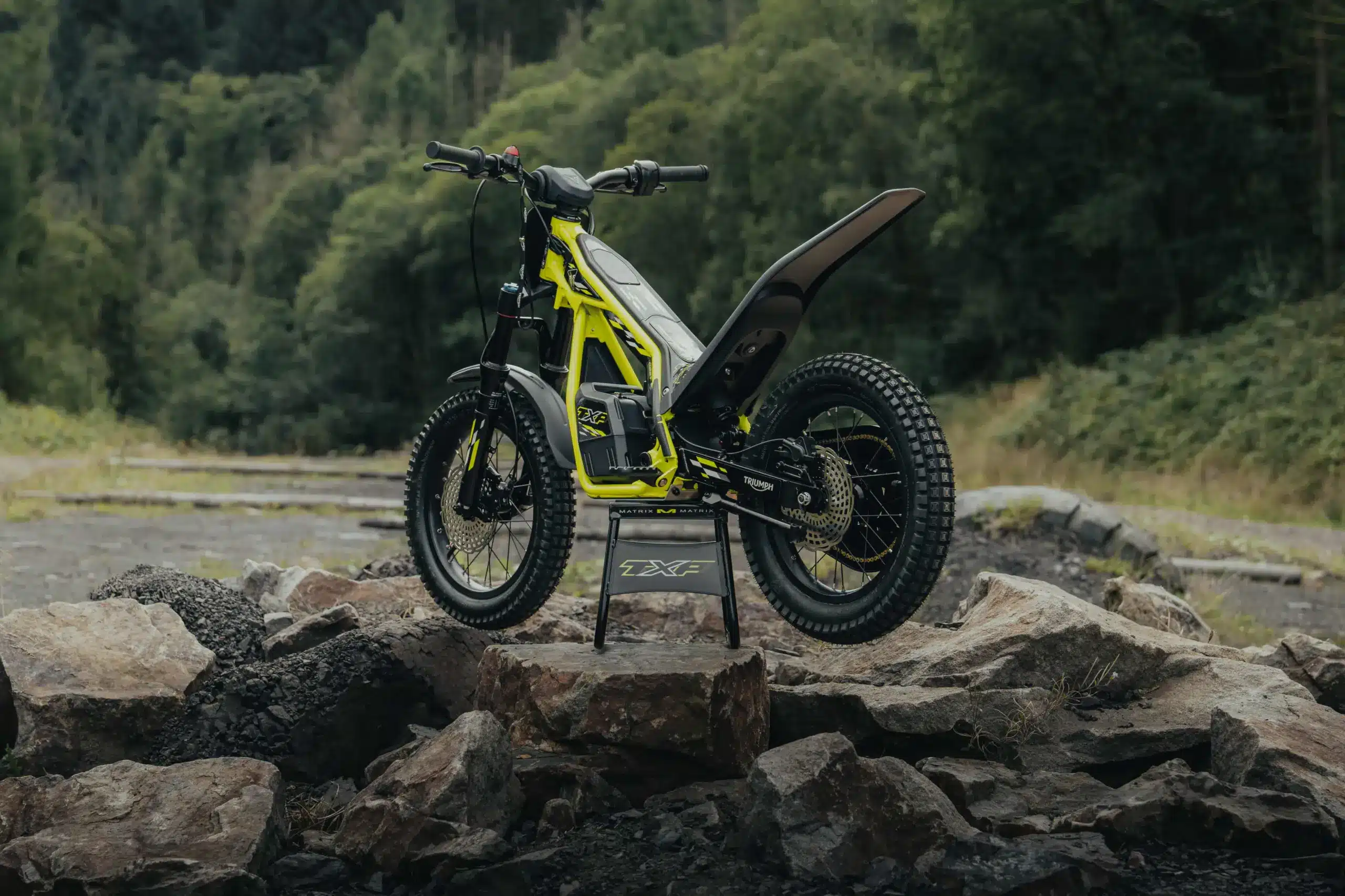 Triumph TXP-16 Elektro-Kinder-Motorrad steht auf Felsen im Gelände, Seitenansicht
